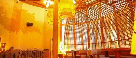 Un restaurante con mobiliario de madera, una columna central y una estructura de techo curva.
