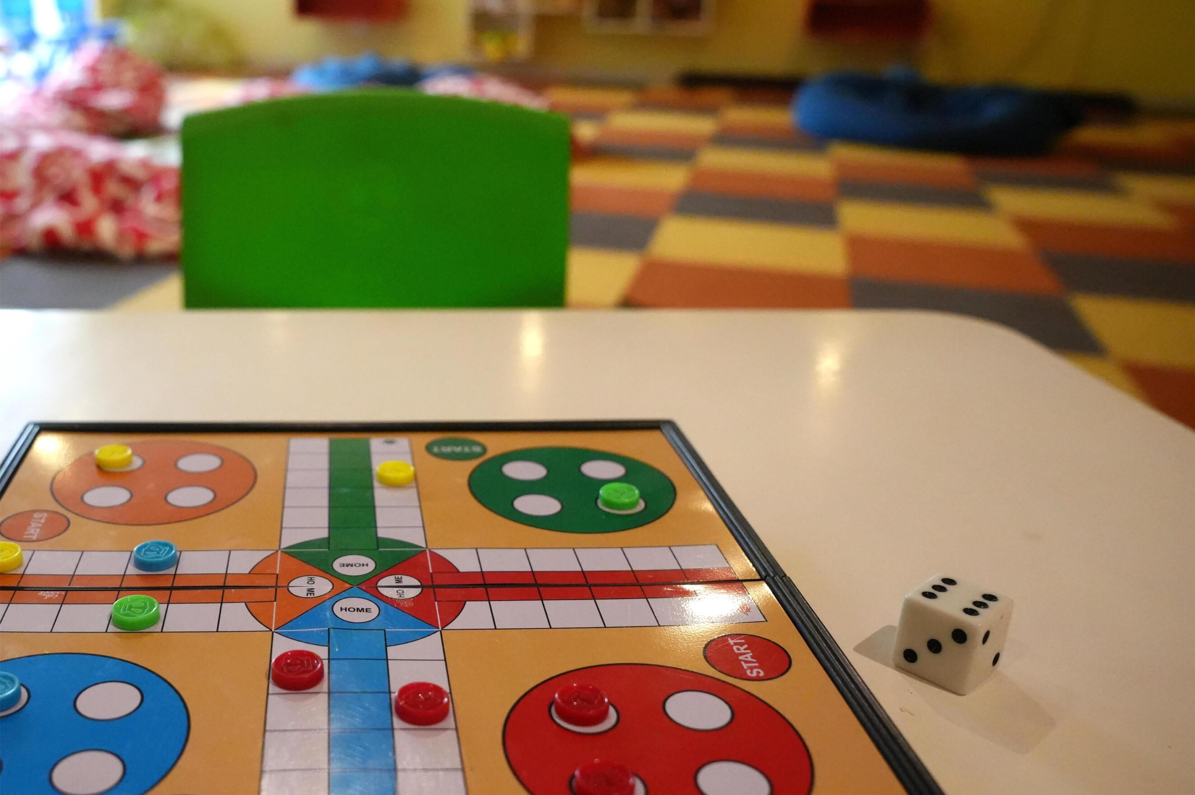 A board game on a table with a dice beside it.