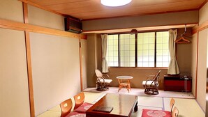 Une pièce de style japonais traditionnel, avec un sol recouvert de tatamis, une basse table en bois et des paravents en papier de riz (shoji).