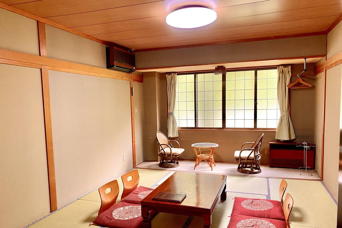 Une pièce de style japonais traditionnel, avec un sol recouvert de tatamis, une basse table en bois et des paravents en papier de riz (shoji).