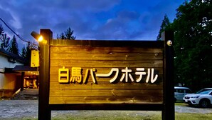 Une enseigne en bois, ornée de caractères japonais, indiquant la présence d’un hôtel.