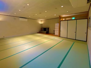 Una habitación con esteras de tatami, disposición tradicional japonesa, un fusuma y una pequeña zona de estar con una mesa baja y cojines.