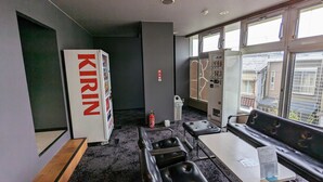 A hotel room with a minibar, a fire extinguisher, a window with a view of buildings, and a seating area with a table and chairs. - Hotel Select Inn Shimada Ekimae (Shimada)