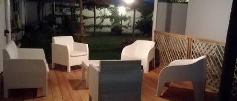 An outdoor patio area with white chairs and a wooden deck.