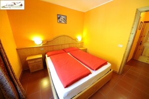 A room with a bed, wooden headboard, two bedside tables, and a nightstand. - Casa Florin (Livigno)