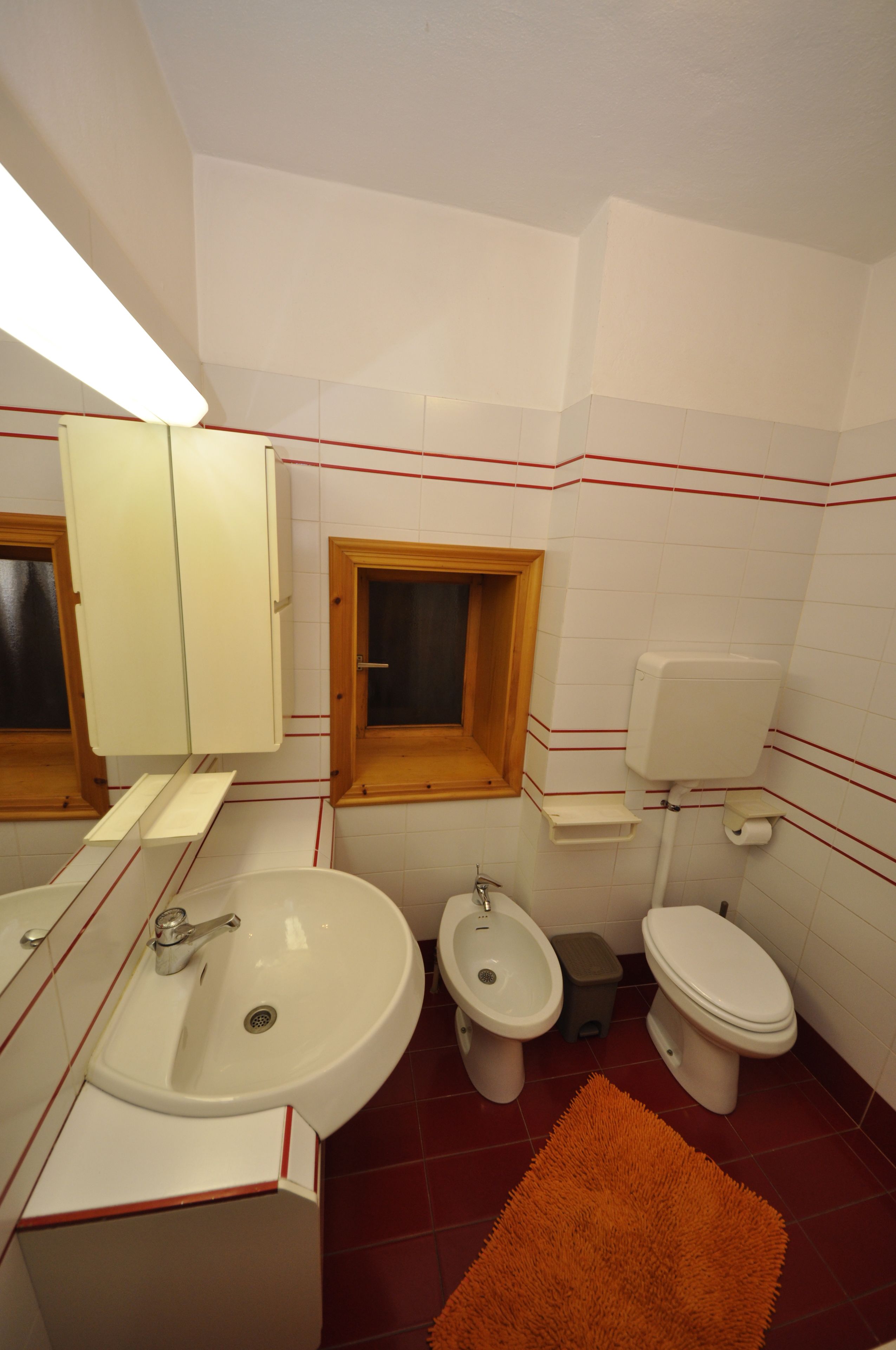 A bathroom with a sink, bidet, toilet, and a window.