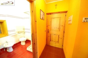 A narrow hallway with a wooden door, a small window, and a wall-mounted radio. - Casa Florin (Livigno)
