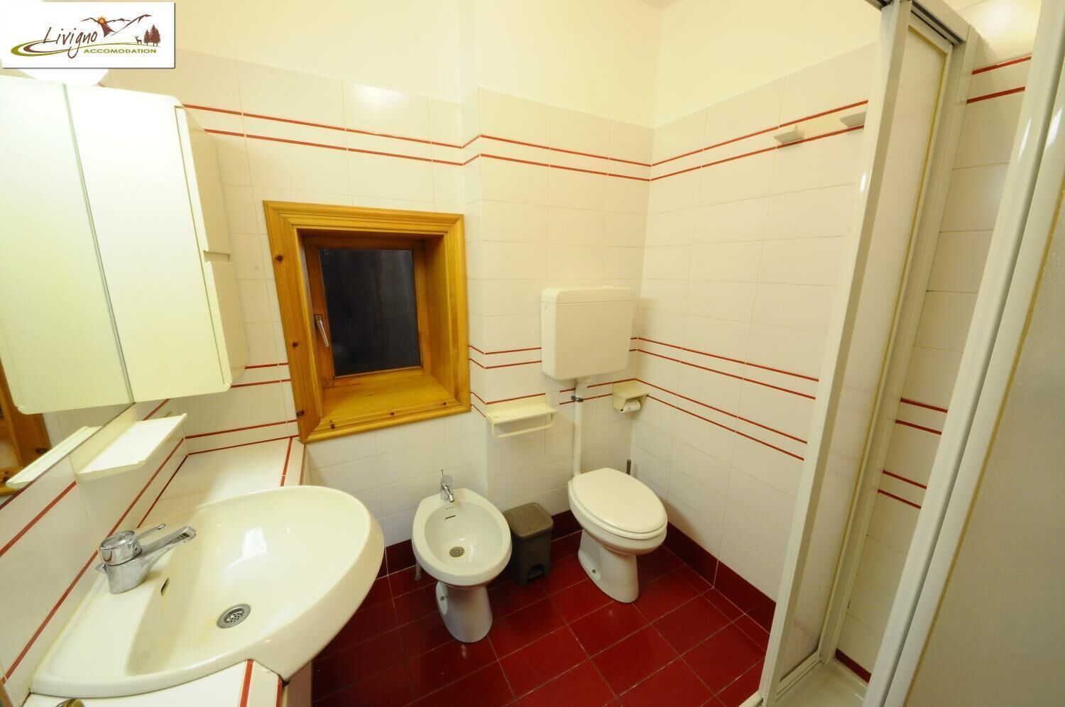 Un baño con lavamanos, bidé, inodoro y ventana.