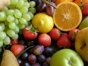 A variety of fruits including grapes, strawberries, plums, oranges, and apples. - Leonardo's Guest House (Swansea)