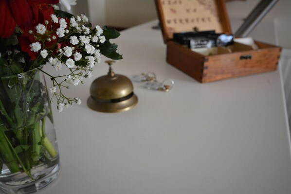 Una mesa con un jarrón de flores, una campana y una caja de madera con objetos.