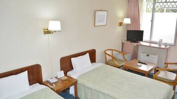 A hotel room with two beds, a desk, a television, and a window with a view.