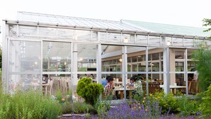 A greenhouse-style building with large glass windows and a roof, surrounded by lush greenery and flowers. - Karuizawa Hotel PAIPU NO KEMURI (Karuizawa)