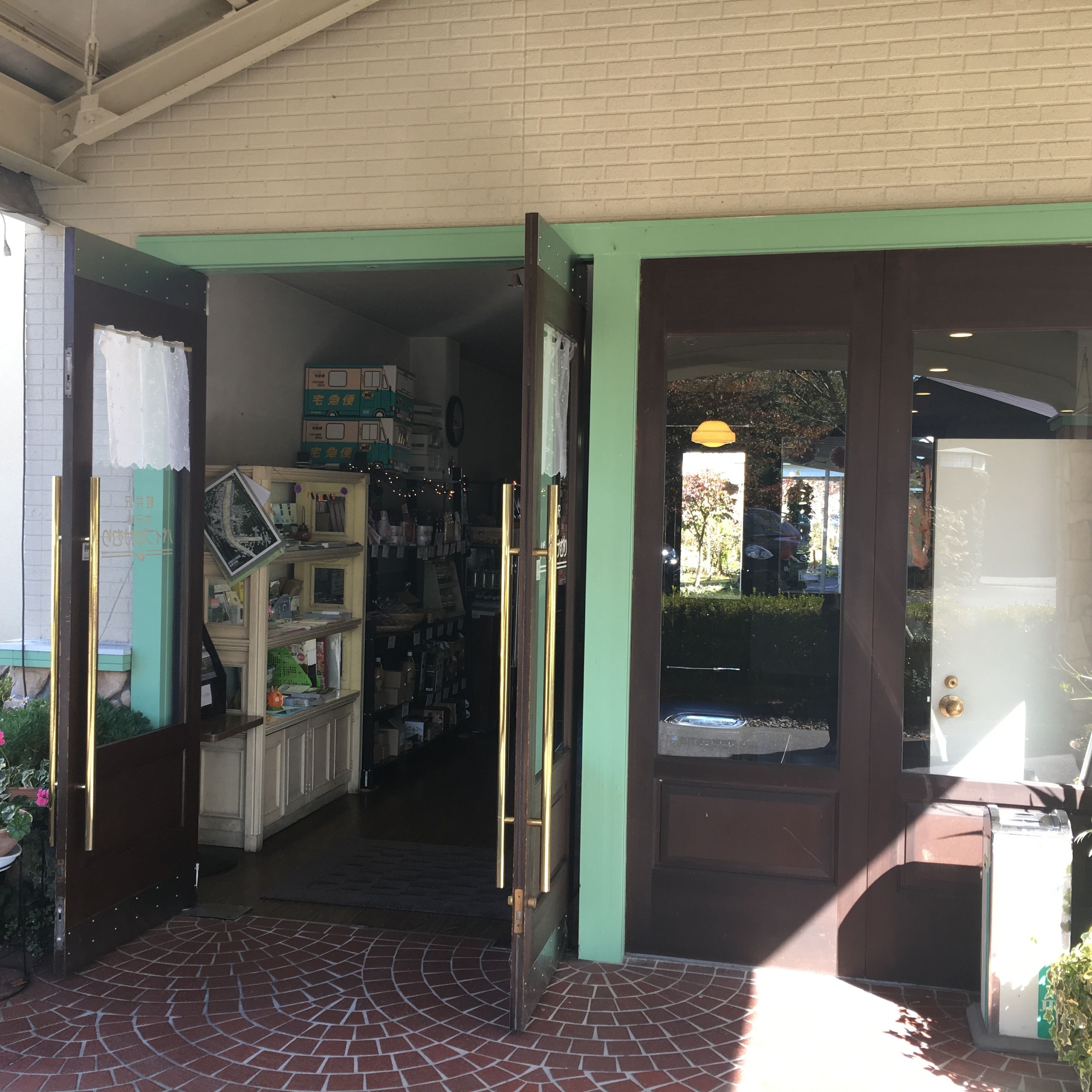 Une devanture de magasin avec un auvent vert, une porte dotée d’une poignée en laiton et un seuil carrelé.