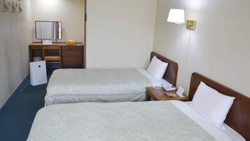 A hotel room with two beds, a desk with a mirror, a lamp, and a small refrigerator.