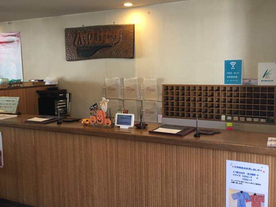 A reception desk with a wooden finish, a computer monitor, a sign indicating free Wi-Fi, and a display of shoes.