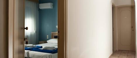 A hotel room with a bed, a nightstand, and an air conditioning unit on the wall.