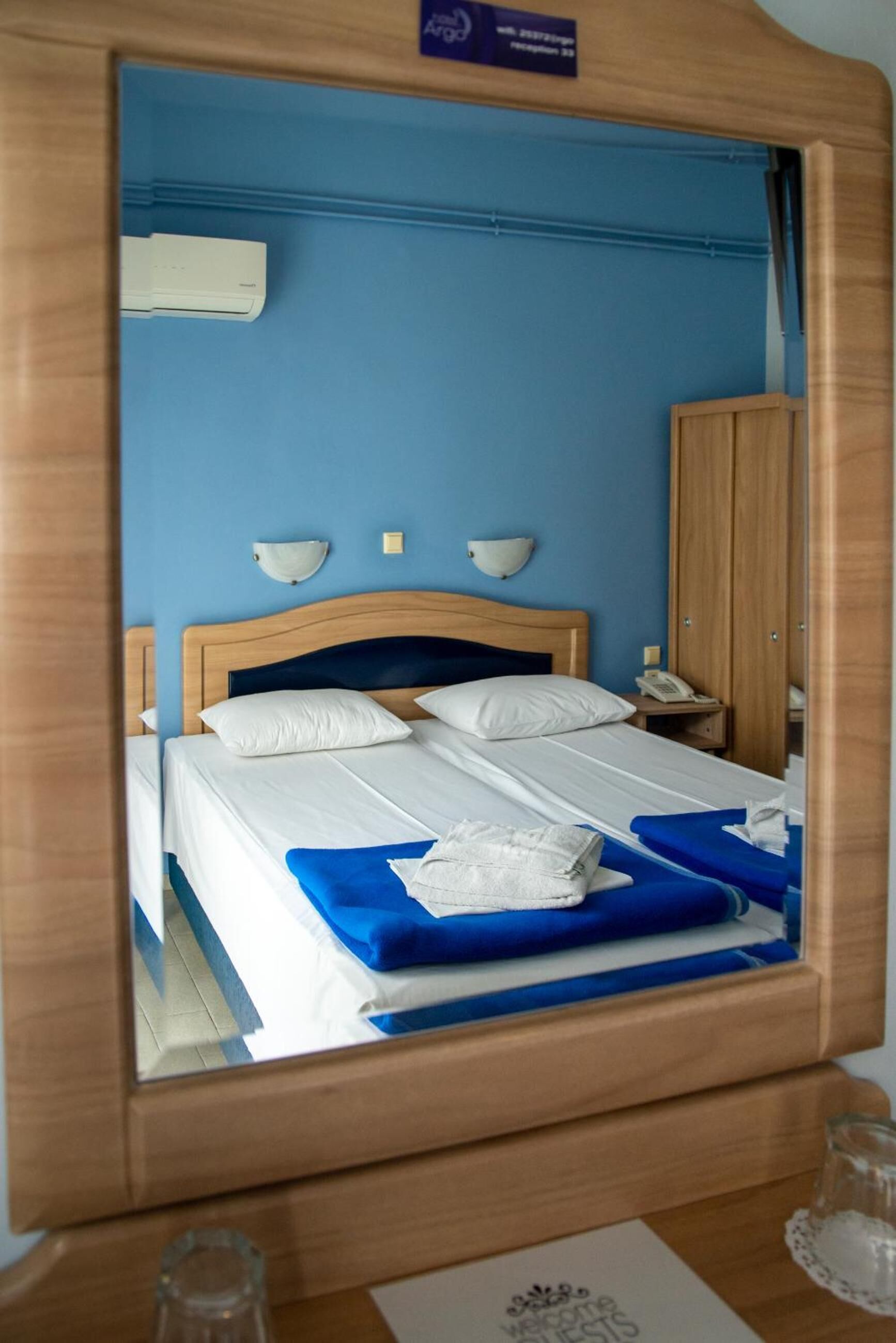 Una habitación de hotel con una cama grande, un cabecero de madera, una mesita de noche con lámpara y un armario.