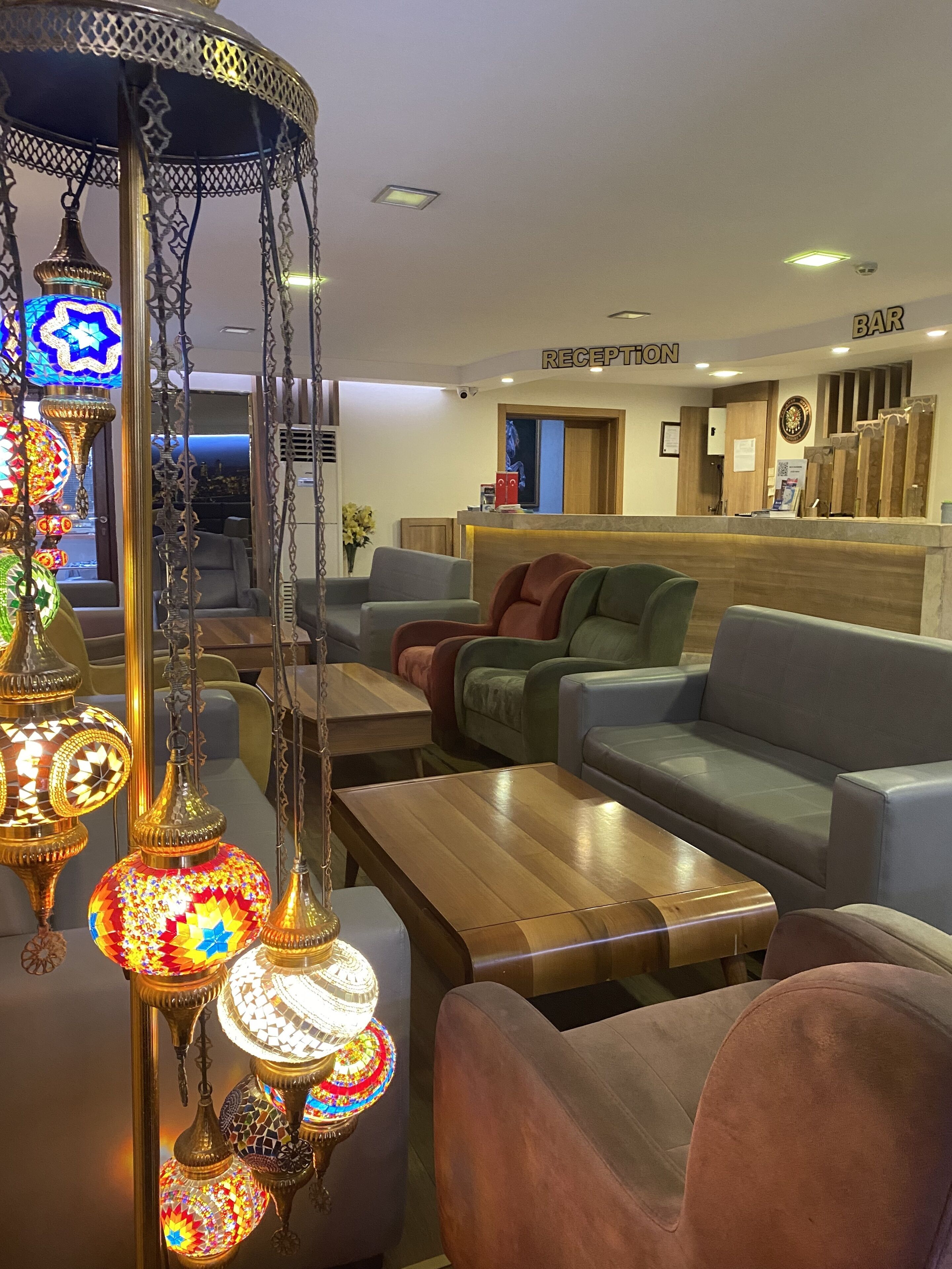 Un vestíbulo con mostrador de recepción, sofás y lámparas decorativas colgantes.
