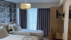 A hotel room with two beds, a desk, a chair, a TV, and a large window with curtains. - Polanin Hotel (Istanbul)
