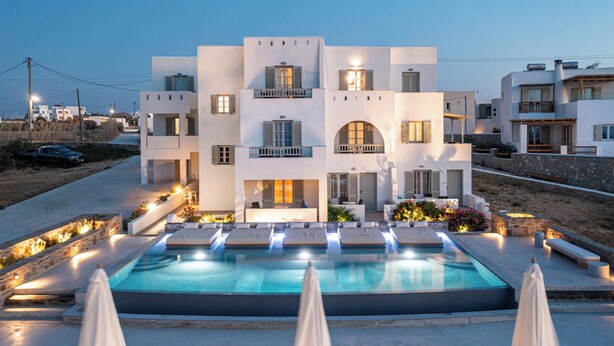 A modern hotel with a swimming pool, outdoor seating, and a view of the surrounding area. - Agnanti Hotel (Naxos)
