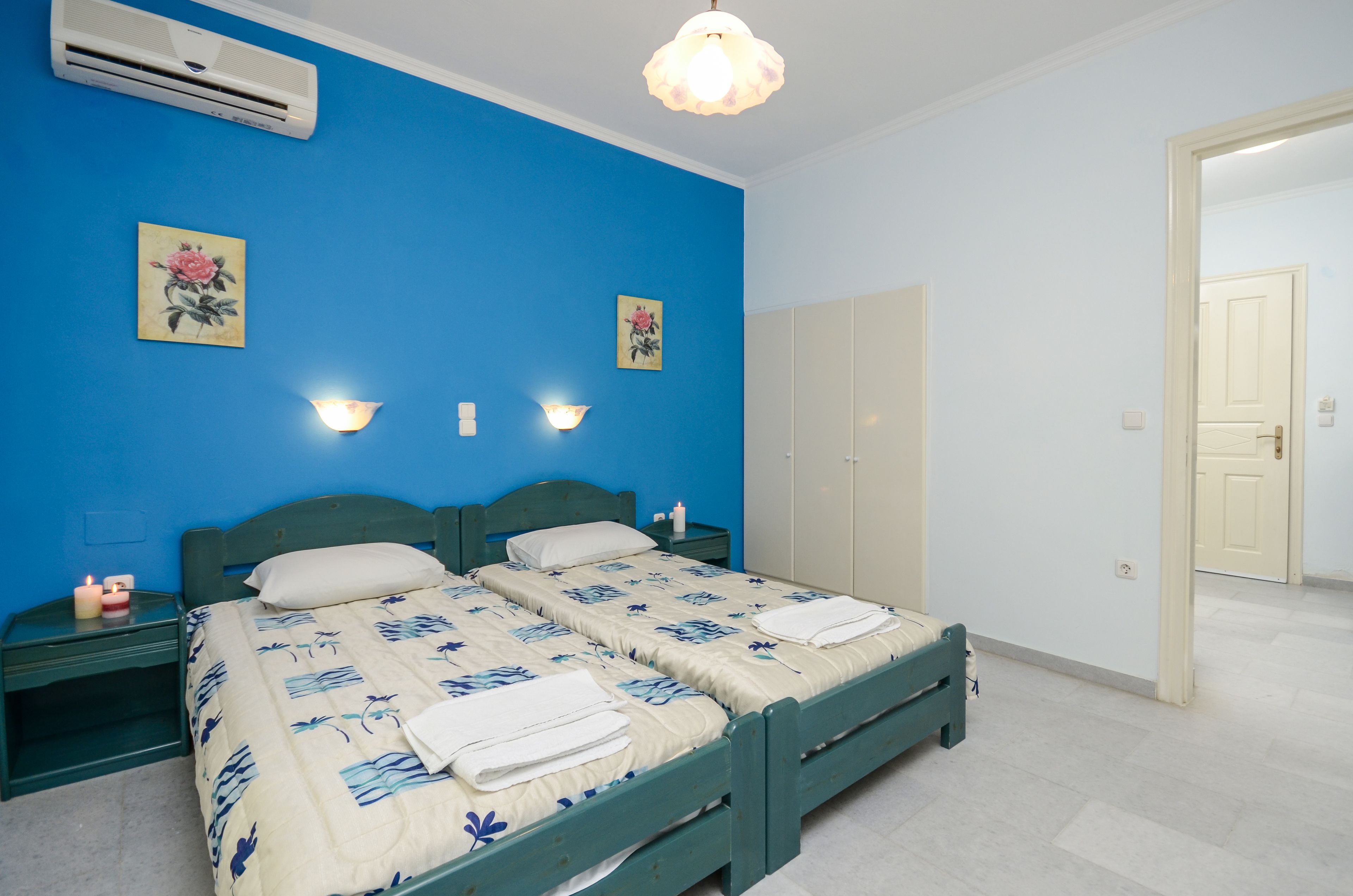 Une chambre avec deux lits, une table de chevet avec une lampe, des appliques murales et un climatiseur.