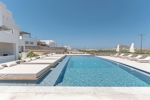 A swimming pool with lounge chairs and a stone wall.
