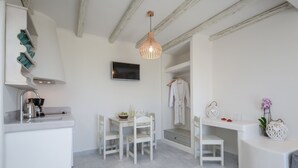 A modern, minimalist kitchen with white cabinetry, a built-in stove, and a hanging light fixture. - Agnanti Hotel (Naxos)