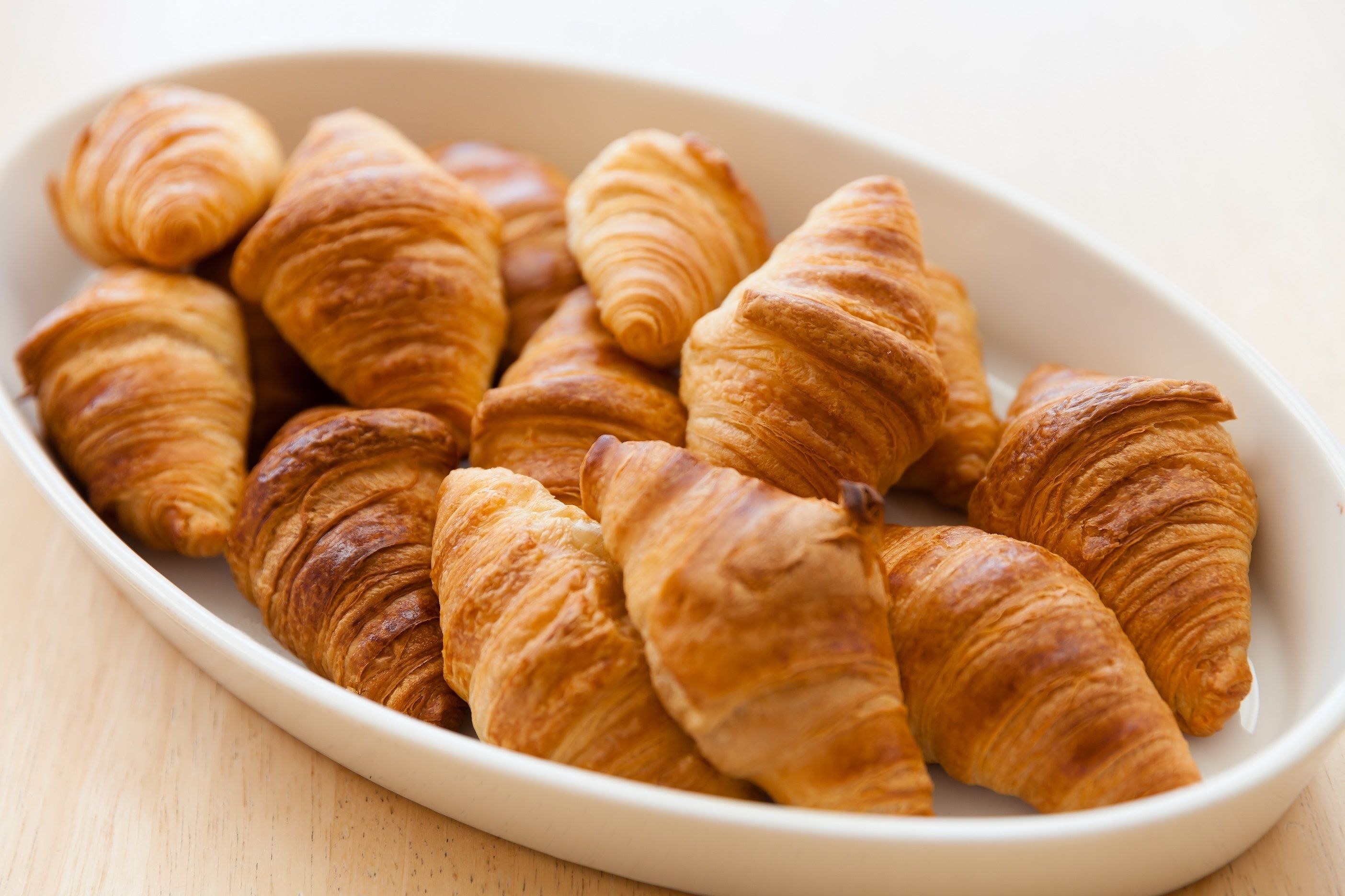 A white oval dish containing several golden-brown croissants.