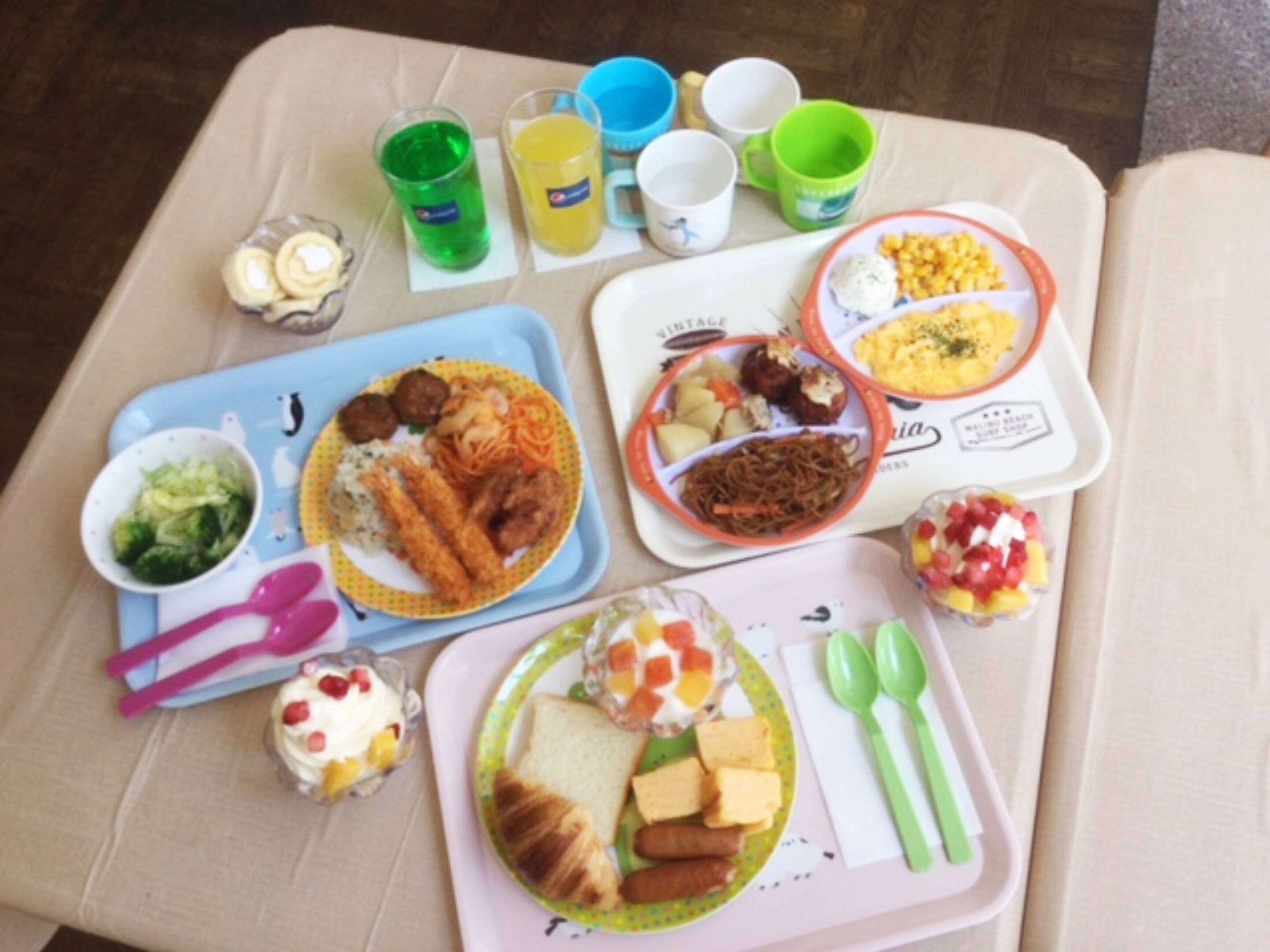 Un plateau repas contenant divers plats, notamment des boulettes de viande, des légumes et du pain, ainsi que des tasses et un verre de jus de fruits.