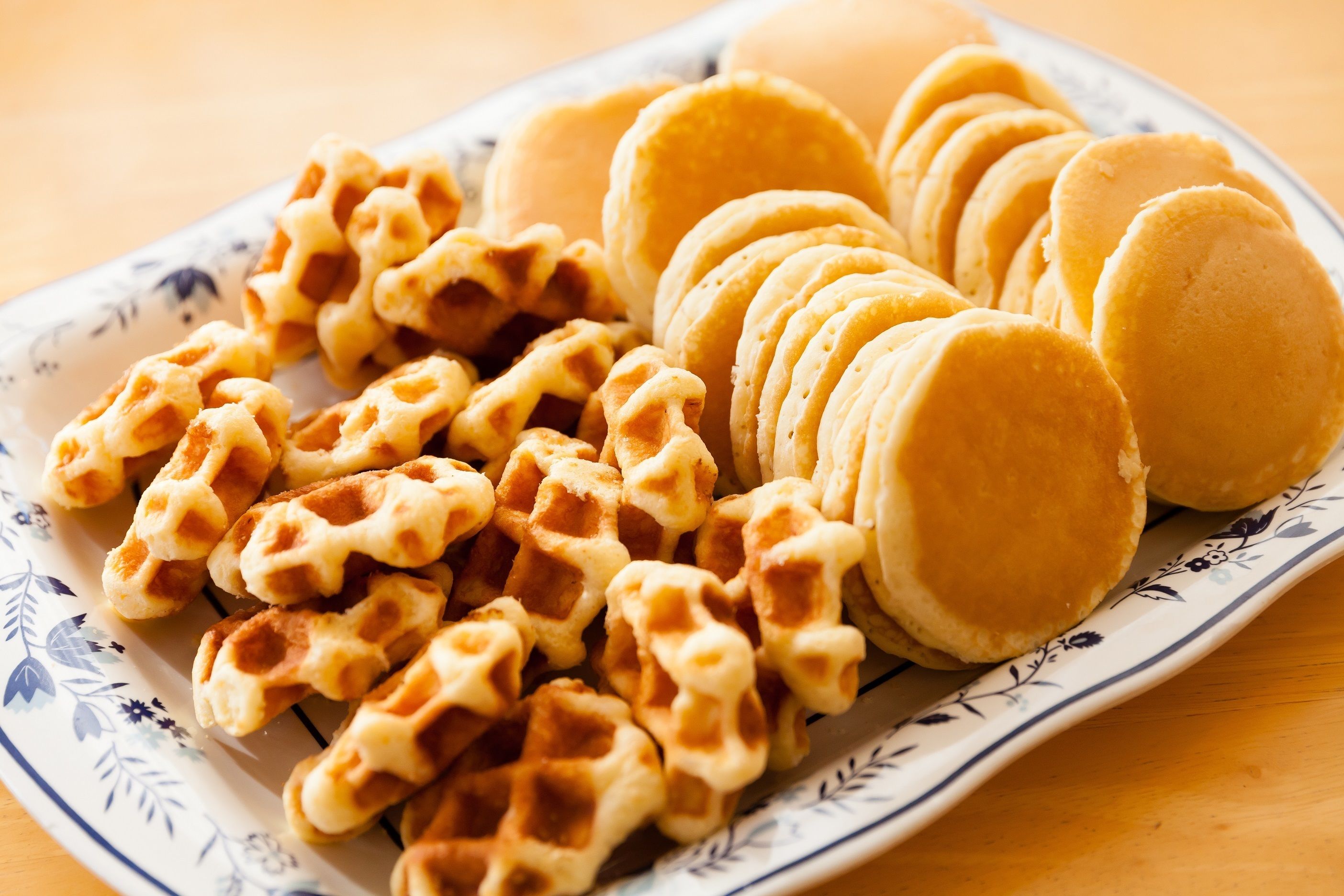 Une assiette de gaufres et de crêpes, le tout présenté sur une assiette à motifs floraux.