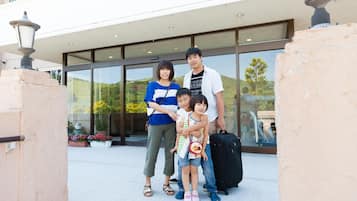 A family of four standing in front of a building with large windows and a balcony.