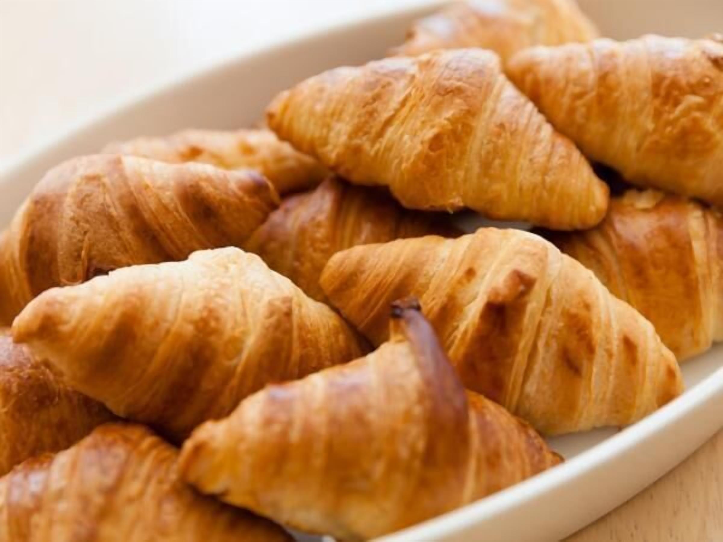 Un plato blanco con varios croissants dorados y crujientes.