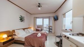 Ein Hotelzimmer mit zwei Betten, einer Küchenzeile, einem Essbereich und einem Balkon mit Blick.
