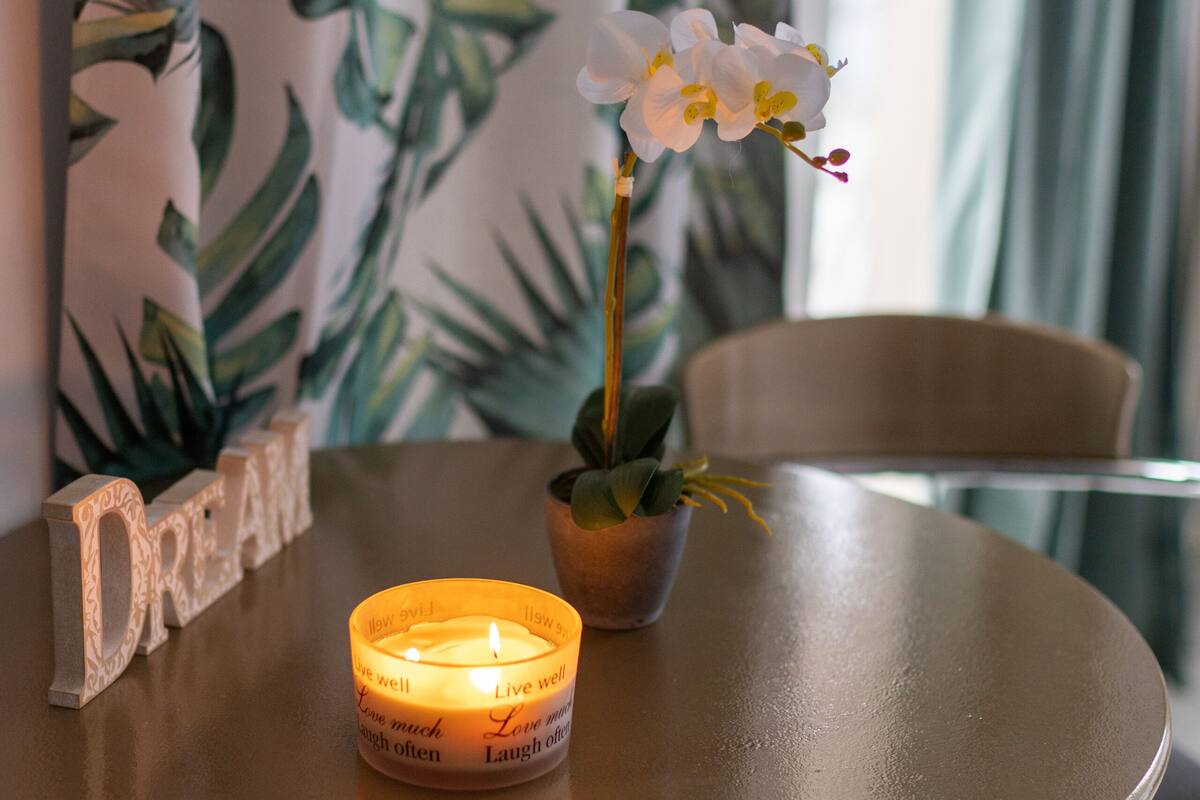 Une table ronde avec une bougie et une orchidée en pot.