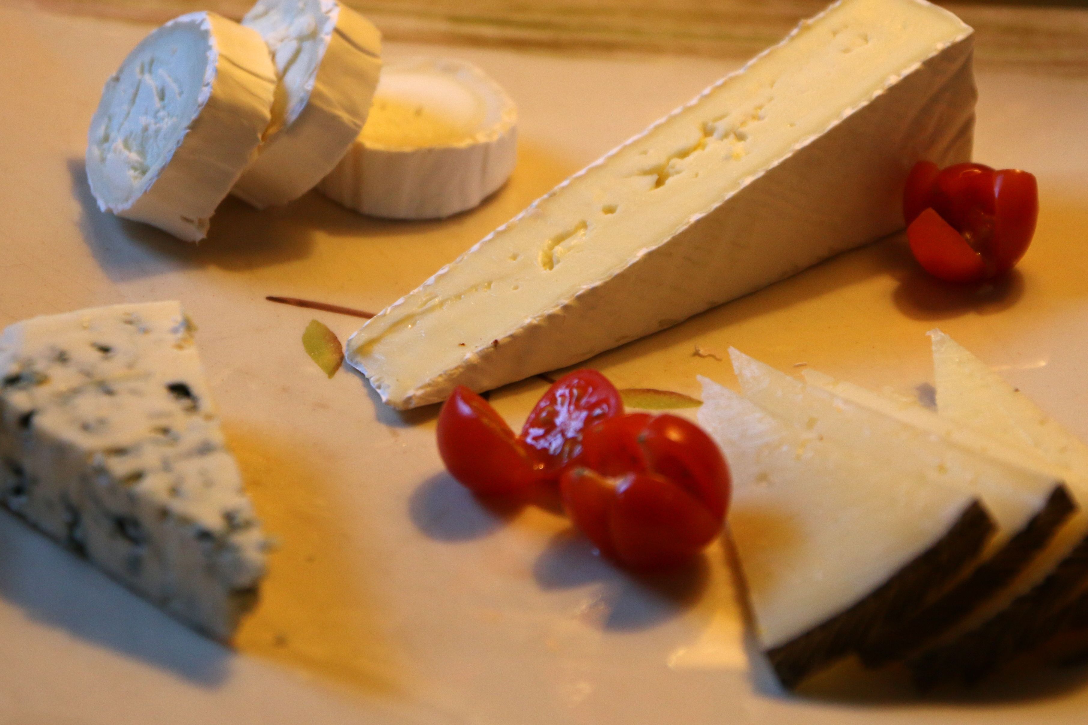 Diversos queijos em um prato, incluindo um pedaço grande de queijo branco e um pedaço menor de queijo azul.