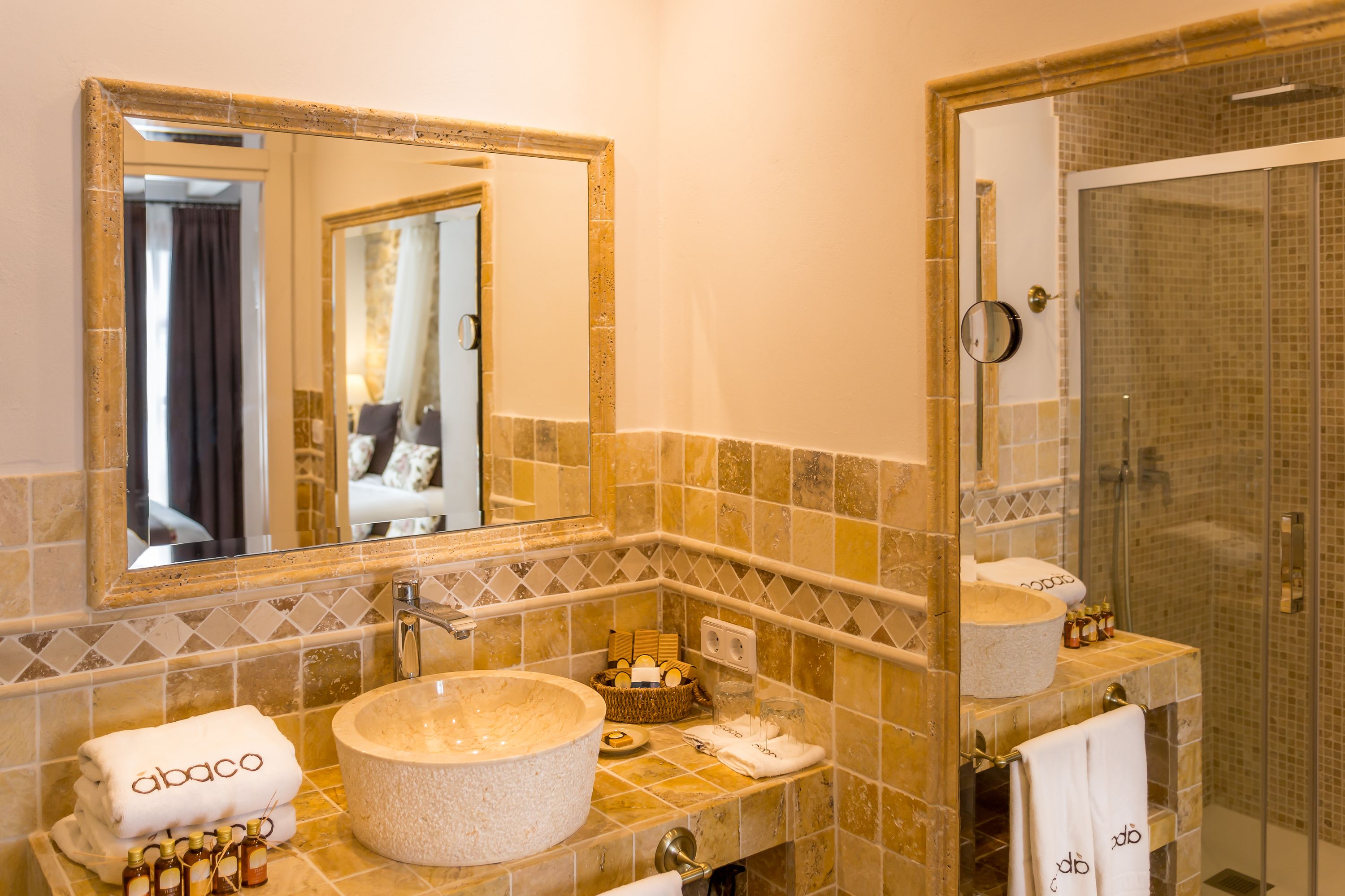 A bathroom with a large mirror, a round sink, and a shower area.