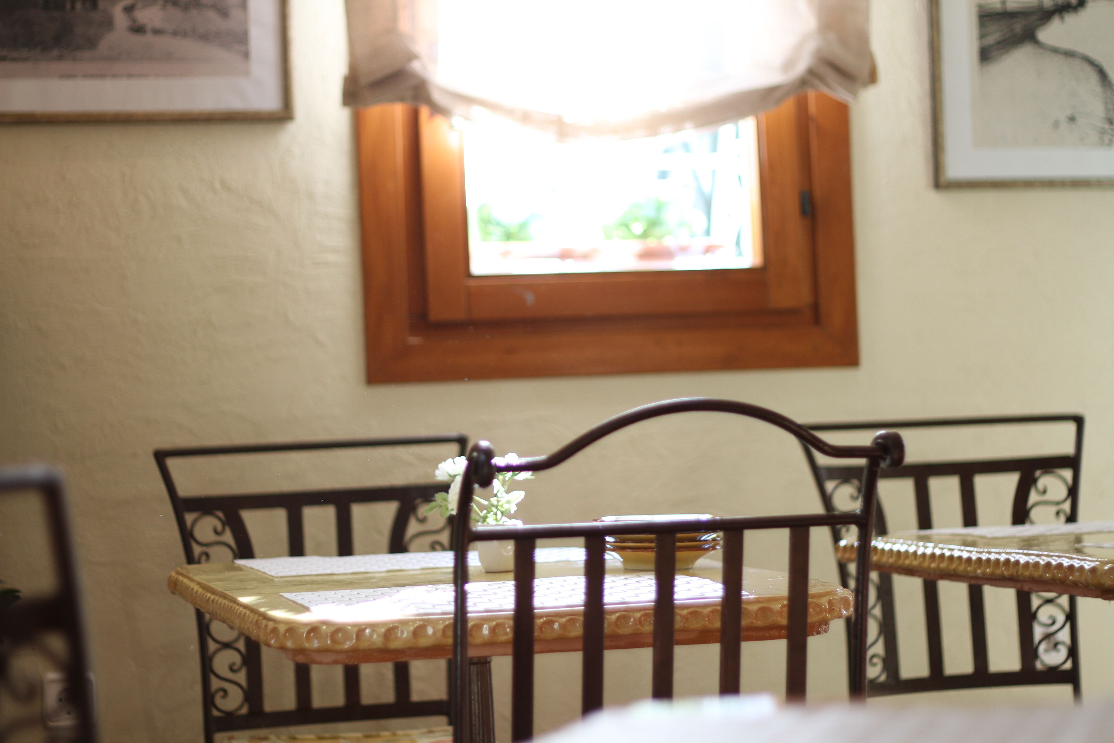 A dining area with a table and chairs, a window with a curtain, and a framed picture on the wall.