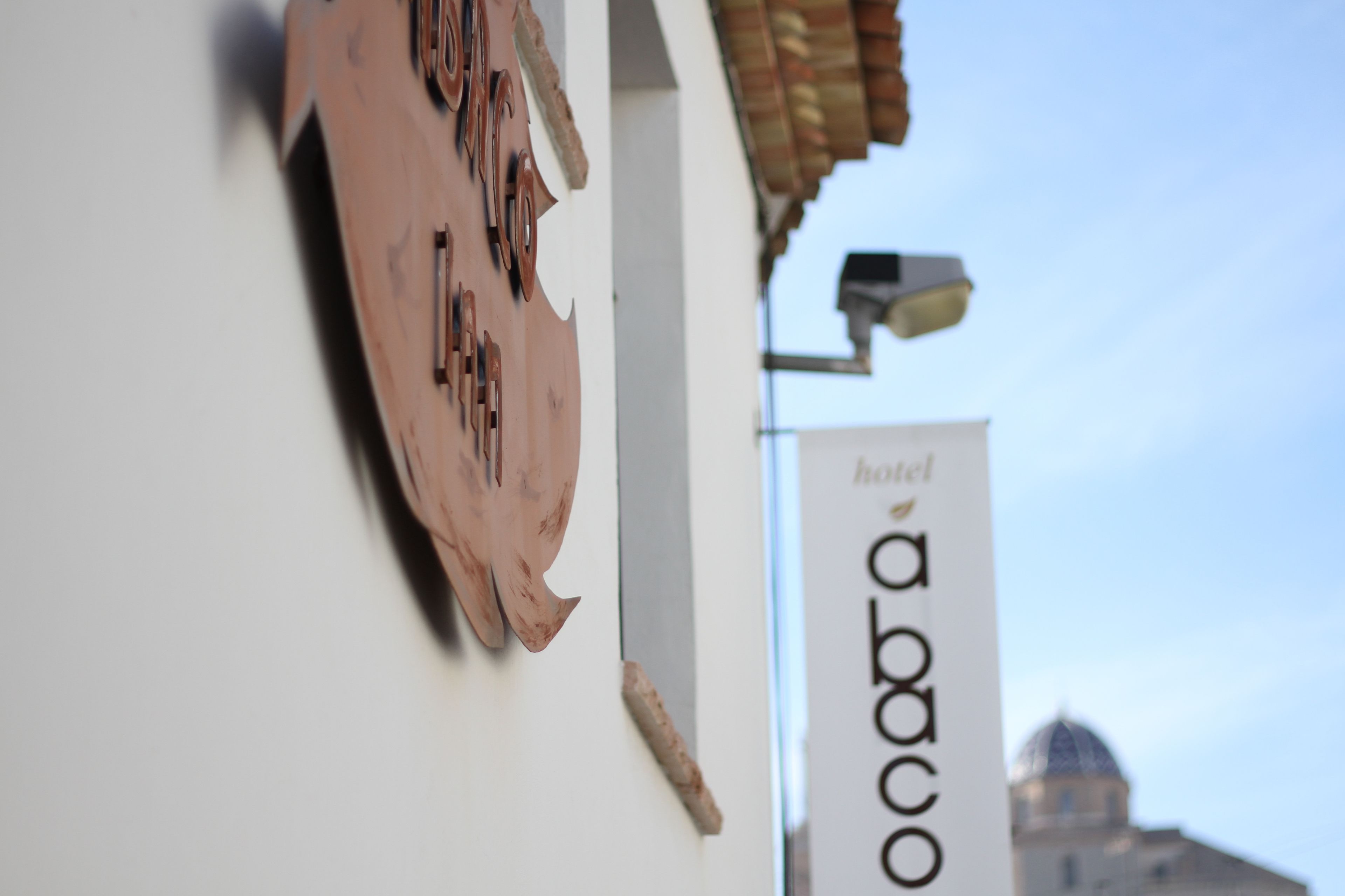 A building with a sign that reads "abaco hotel" and a part of a building with a dome in the background.