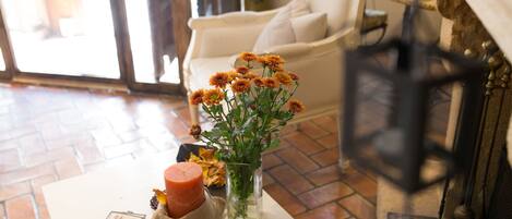 Una habitación acogedora con un sofá blanco, una mesita con una vela y flores, y una chimenea.