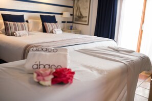 A hotel room with two beds, each with a white bedspread and pillows. There is a small table with a flower arrangement in front of one bed. - Hotel Ábaco Altea (Altea)