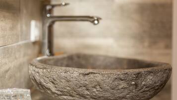 A stone basin with a modern faucet, set against a tiled wall.