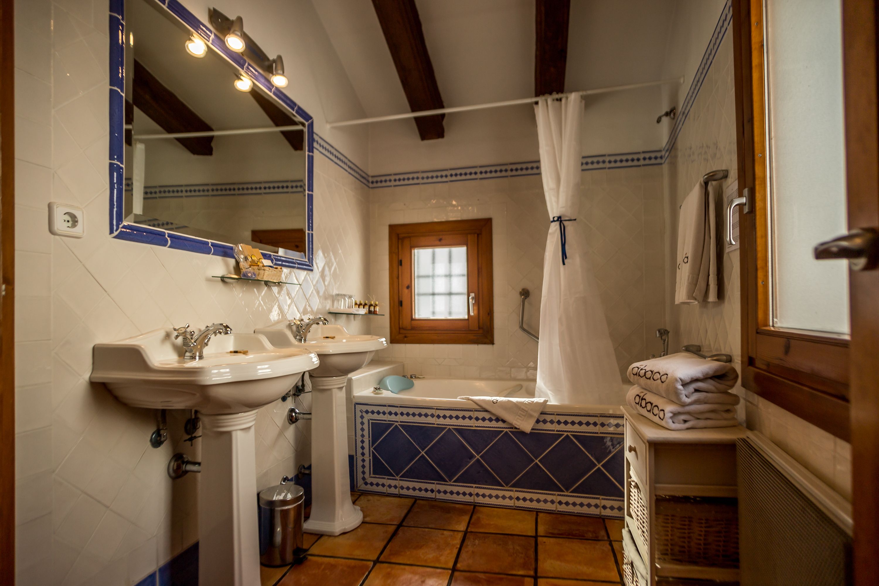 Een badkamer met twee wastafels, een bad en een raam.