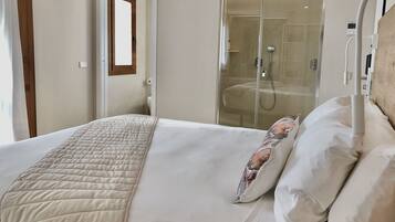 A hotel room with a bed, a glass shower enclosure, and a wooden door.