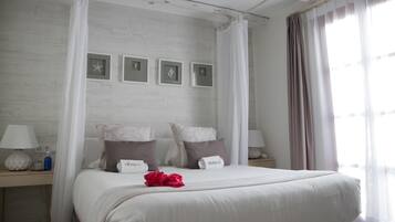 Une chambre à coucher comprenant un lit, deux tables de chevet, une commode, une fenêtre avec des rideaux et des cadres photo accrochés au mur.