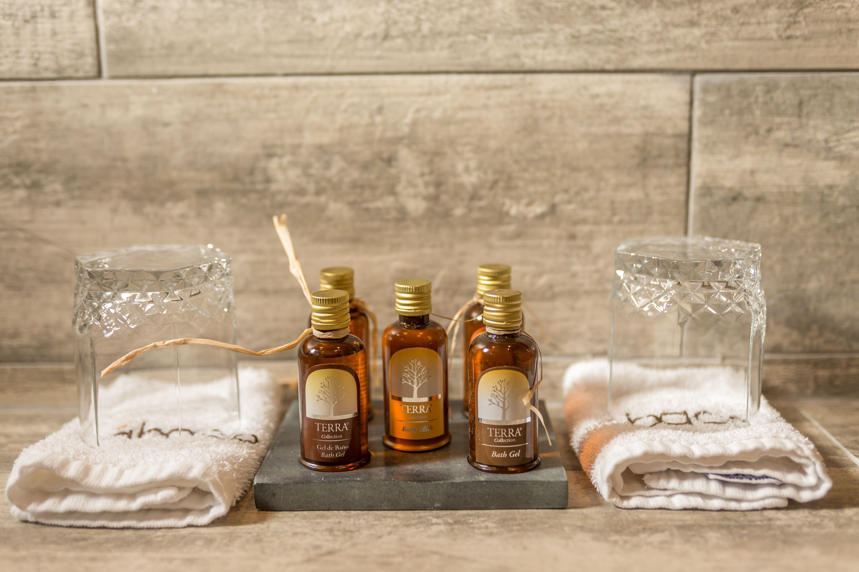 Four bottles of Terra Bath Gel on a wooden surface with two clear glass bottles on either side.