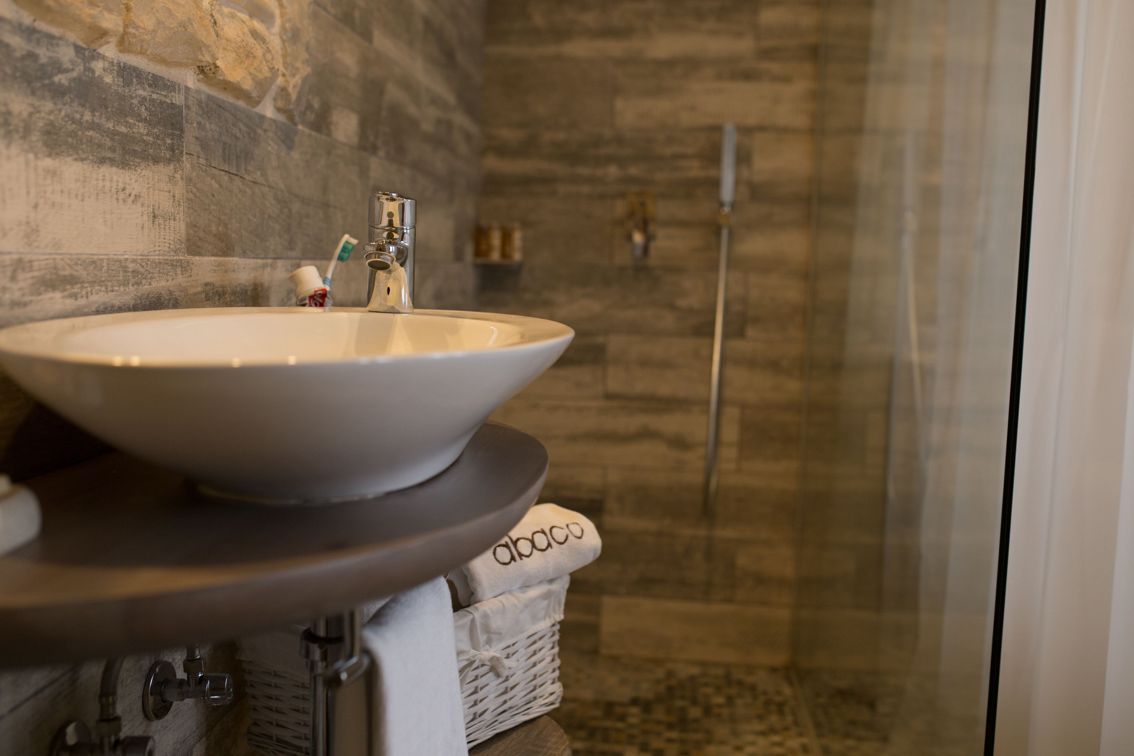A bathroom with a large, round sink, a shower area, and a towel rack.