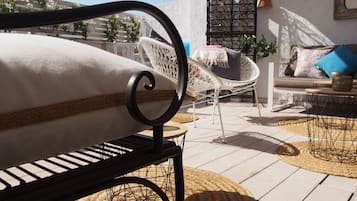 Relax in a serene outdoor seating area with a woven bench, wicker chair, and round rug.