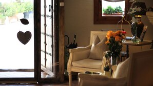 A room with a beige armchair, a small table with a vase of flowers, and a window with a view of greenery outside. - Hotel Ábaco Altea (Altea)