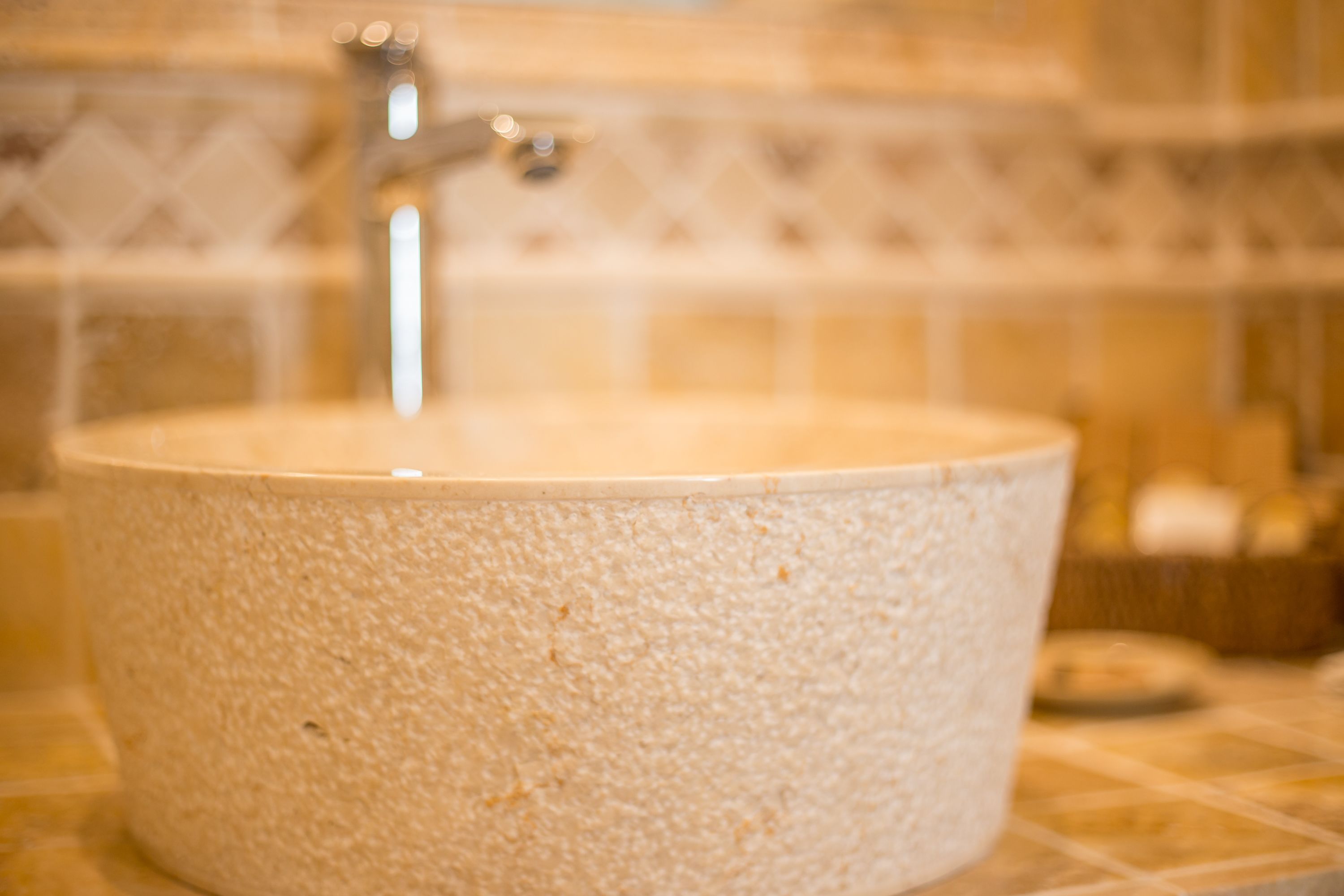 A bathroom with a round, textured sink and a visible faucet.