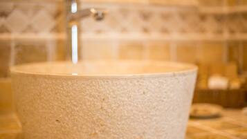 A bathroom with a round, textured sink and a visible faucet.